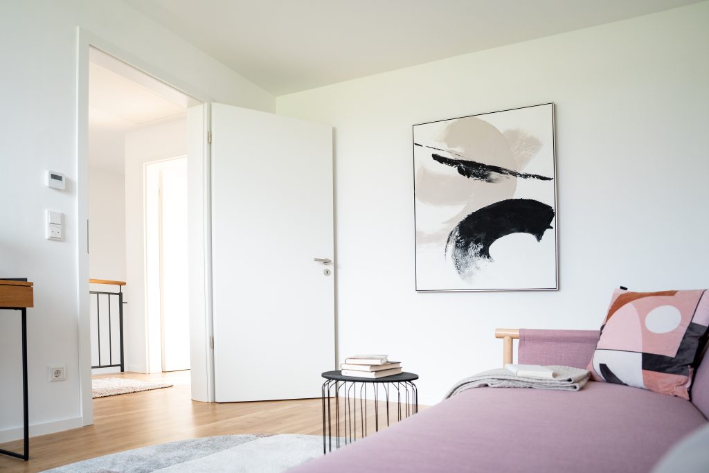 Helles Zimmer mit Sofa und weißer Tür.