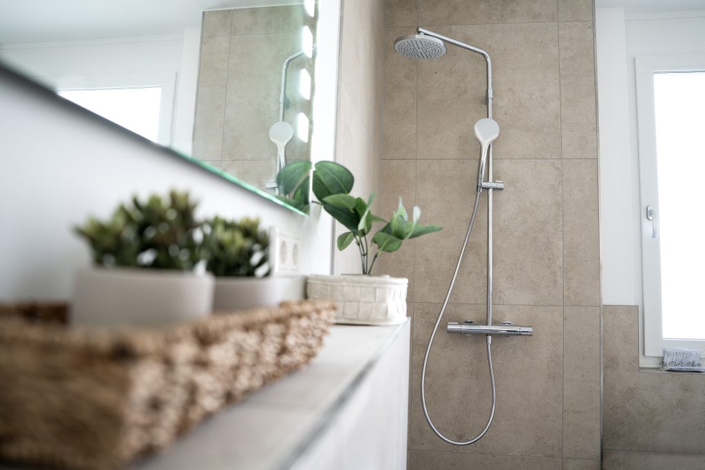 Bad mit Dusche und beigen Fließen.