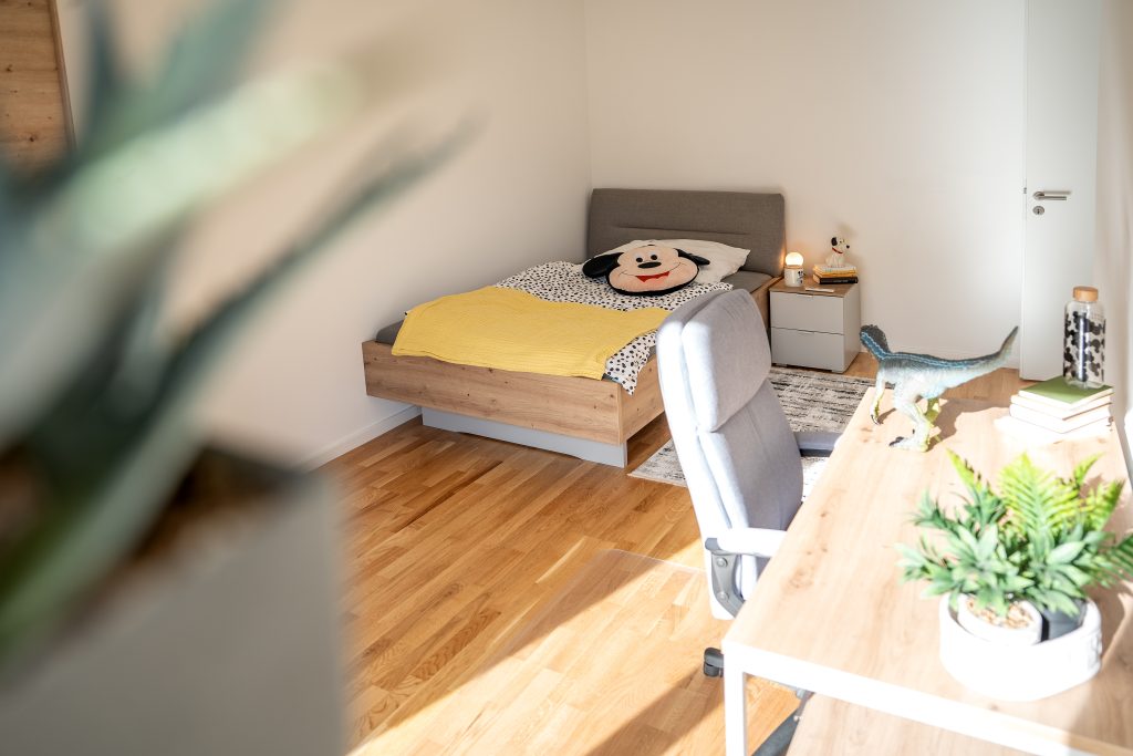 Blick in ein helles Schlafzimmer mit Holzboden.