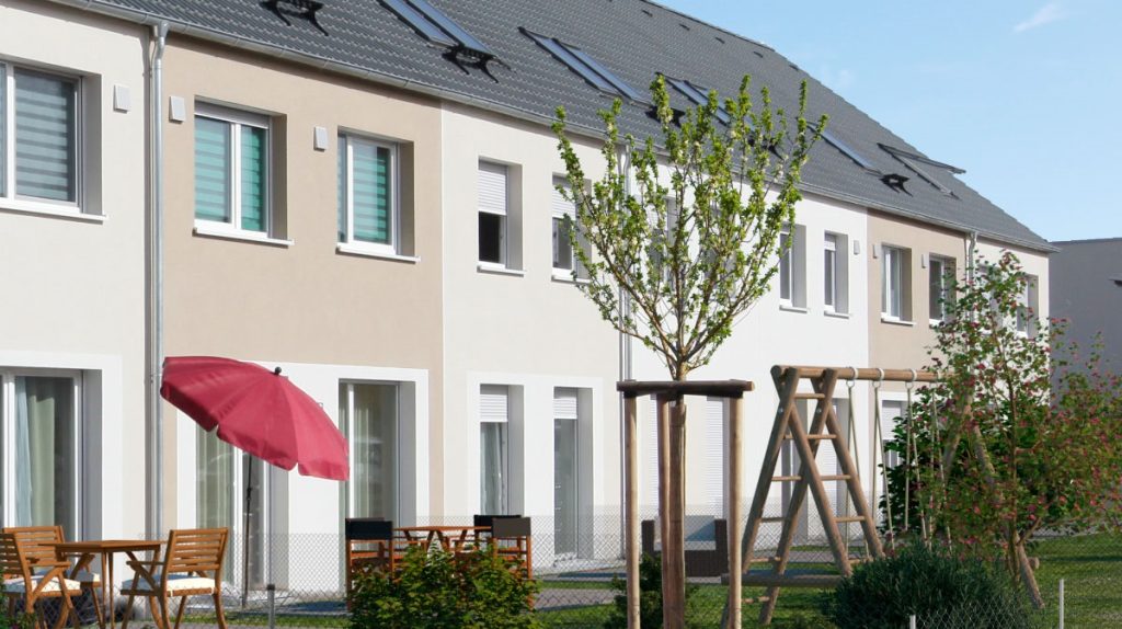 Reihenmittelhäuser mit grauem Satteldach und Garten.